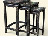 trois tables gigognes noires ornées de motifs floraux sur fond blanc
