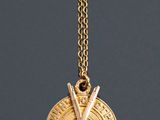 a close up of a gold necklace with two crossed swords on it