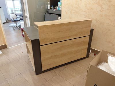 un comptoir d'accueil en bois dans une pièce, devant lequel se trouve un carton