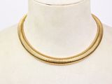 Le collier est en métal doré et présente un motif imitant la peau de serpent.