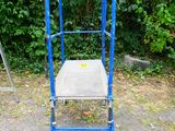 a blue metal chair sitting in the middle of a parking lot