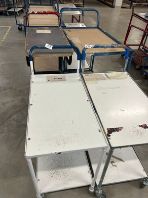 de nombreuses tables et chariots dans un entrepôt, sur lesquels sont empilés de nombreux cartons