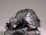 bronze statue of a bird on a rock with a bird on it ' s back