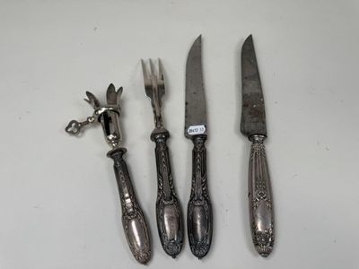 trois couteaux et une fourchette posés sur une table, avec une étiquette dessus