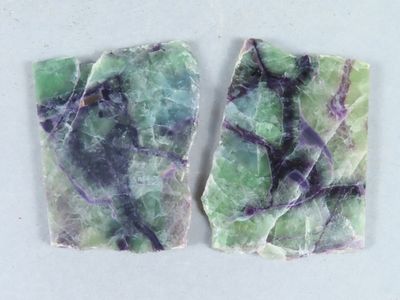 deux morceaux de marbre vert et violet posés sur une surface blanche