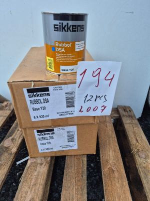 un carton de peinture posé sur une palette, à côté d'un carton de bois