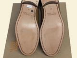 pair of tan leather shoes with black straps on top of a cardboard box