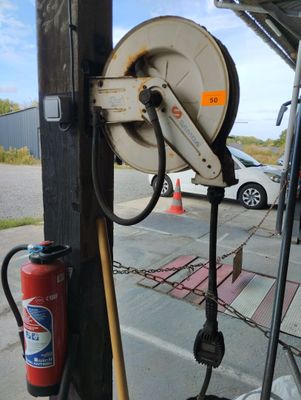 a hose attached to a pole with a fire extinguisher nearby