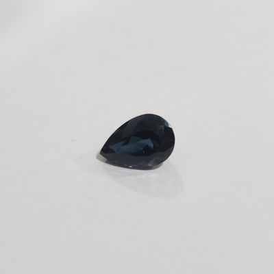 a blue sapphire tear shaped stone on a white surface