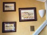 three framed pictures on the wall above the stairs