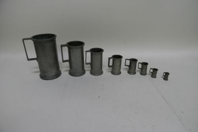 cinq tasses de tailles différentes posées sur une surface blanche