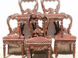four antique chairs with red upholstered seats are sitting against a white wall