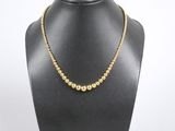 un collier avec une boule en or autour du cou d'un mannequin, sur fond blanc