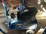 un petit compresseur d'air bleu posé dans un garage