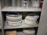 many plates and glasses on a shelf in the kitchen