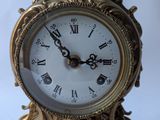 a gold clock that has roman numerals on it