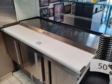 une cuisine équipée d'appareils électroménagers en inox et d'un plan de travail blanc