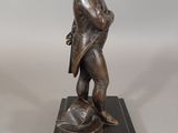 bronze statue of a man standing on a ball on a marble base