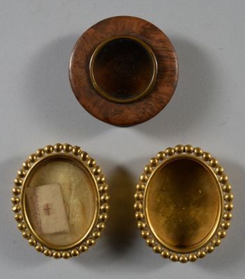 Deux objets plaqués or, l'un orné de l'effigie d'une femme et l'autre de celle d'un homme, sont posés sur une surface blanche