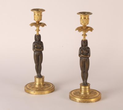 paire de bougeoirs anciens en laiton ornés de figures égyptiennes sur leurs socles