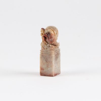 une petite figurine représentant un chien assis sur une bouteille