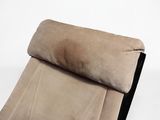 beige and black recliner chair with a pillow on top of it