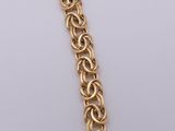 a close up of a gold chain bracelet on a white surface
