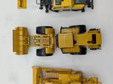 three toy construction vehicles that are on a white surface