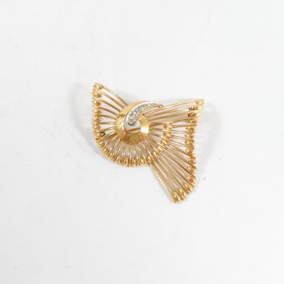 un gros plan d'une broche en or et diamants posée sur une surface blanche