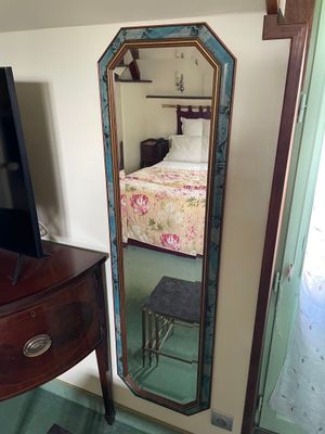 a mirror in the corner of a room with a bed in it