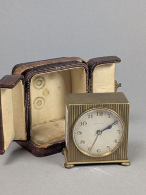 une petite horloge posée dans un coffret sur une table
