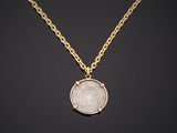 a gold necklace with a coin on a black background