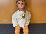 a small doll sitting on the floor in front of a wall