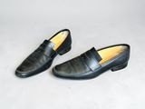 a pair of black loafers on a white surface