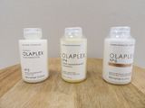 three bottles of olaplex are sitting on a wooden table