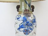 a blue and white vase on a table with a lamp on it