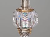 a glass perfume bottle with a gold trim on a white table