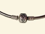 a close up of a silver bead on a black cord