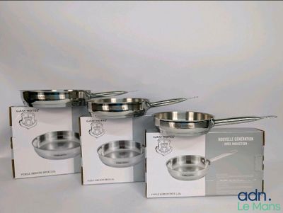 quatre casseroles et poêles en acier inoxydable posées sur un plan de travail blanc