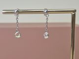 silver plated earrings with clear crystals hanging from them on a stand