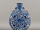blue and white vase with a bird on it on a gray surface