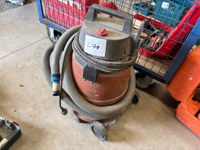une photo d'un aspirateur rouge et gris posé sur le sol, à côté d'un caddie