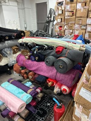 de nombreux rouleaux de tissu posés sur un chariot dans un entrepôt