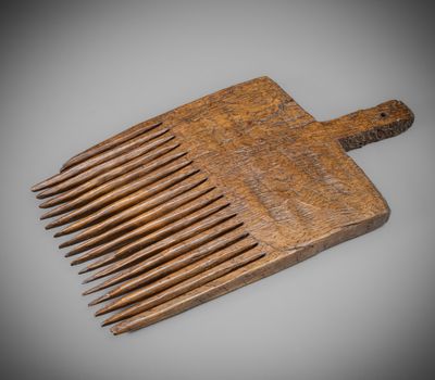 an old wooden comb is sitting on top of a gray surface