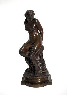 bronze statue of a woman sitting on a rock with her hands on her knees