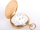 a gold pocket watch sitting on a white surface