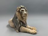 a statue of a lion laying down on the ground