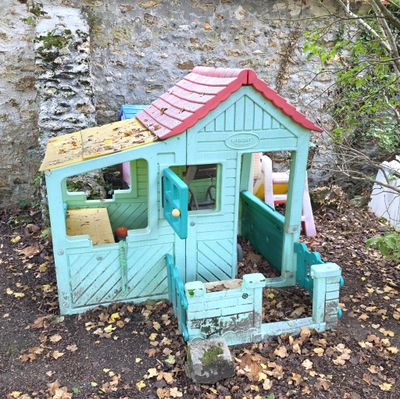 une petite maison en bois avec un toit rouge et une porte verte