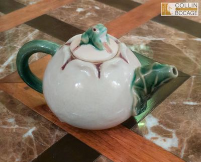 une théière décorée d'une grenouille, posée sur une table