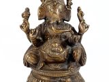 brass statue of a seated gan on a pedestal on a white background